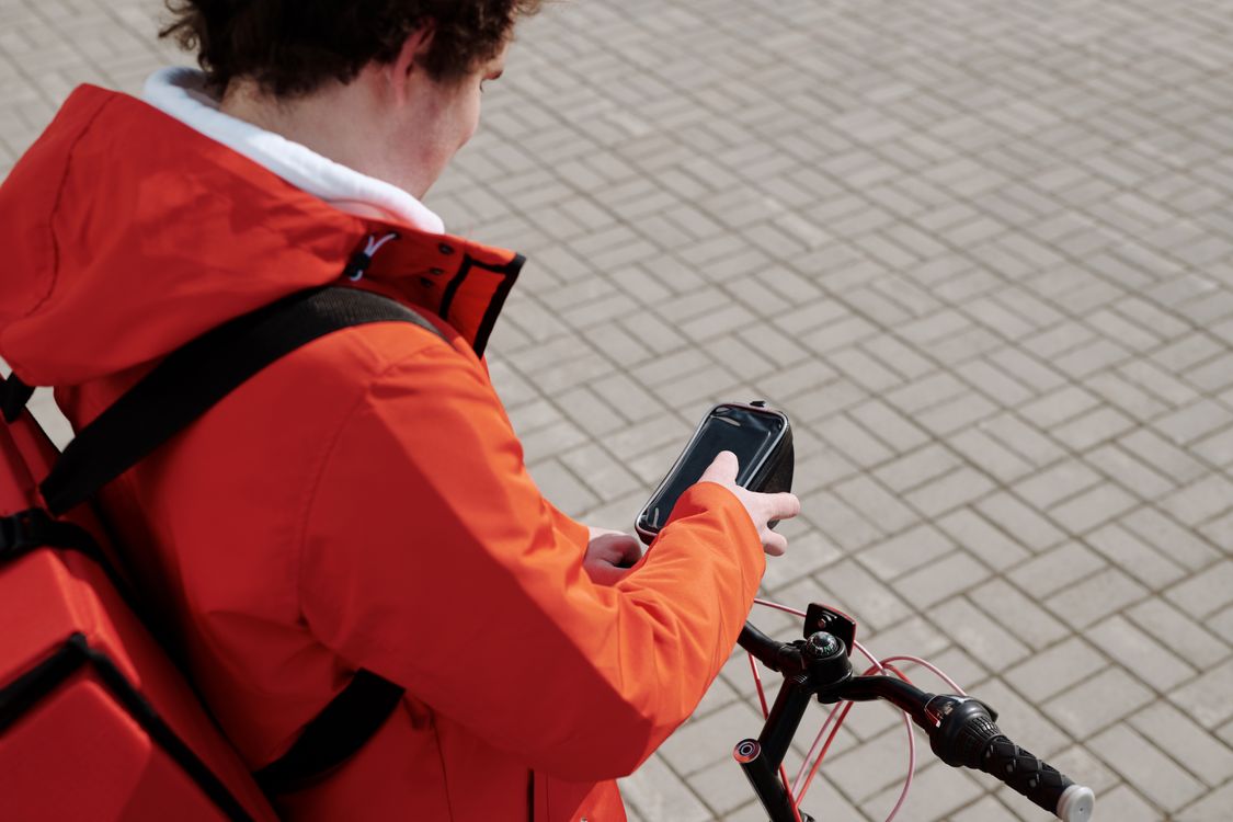 Delivery driver checking smartphone with food delivery apps for DoorDash and Uber Eats