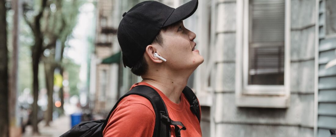 App-based food delivery driver wearing cap and delivery backpack carrying a takeout bag and box