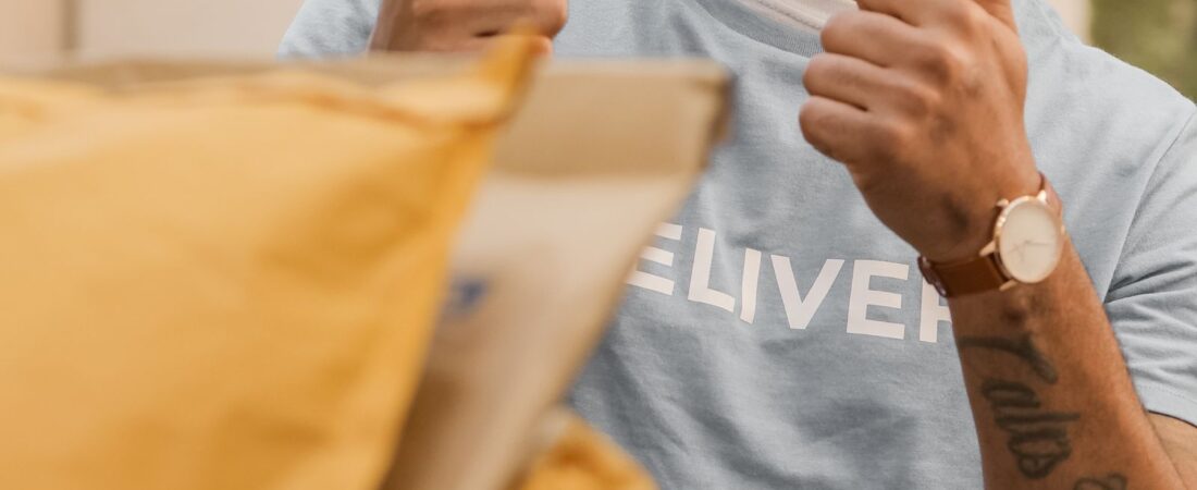 Happy US delivery gig worker in DELIVERY shirt giving thumbs up after handing over an order