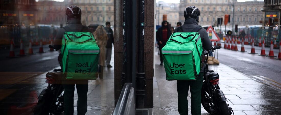 Uber Eats delivery driver checking phone on a city street — real delivery worker photo